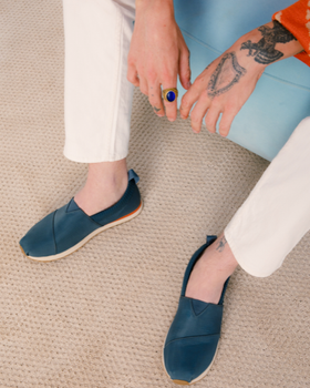 A man sitting wearing navy blue slip-on Tom's shoes
