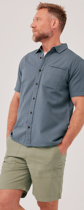 A man wearing a grey short-sleeve Pact shirt and light green shorts