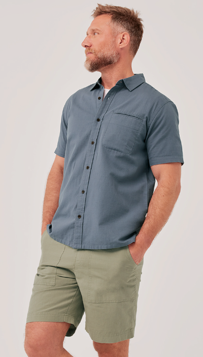 A man wearing a grey short-sleeve Pact shirt and light green shorts