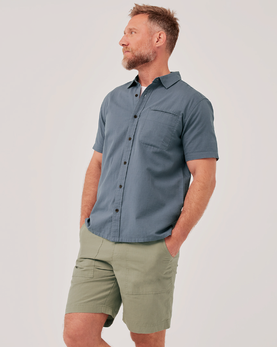 A man wearing a grey short-sleeve Pact shirt and light green shorts