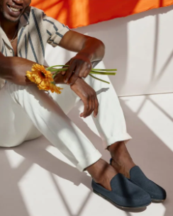 A man sitting with flowers in his hand and Rothy's slip-on shoes on his feet