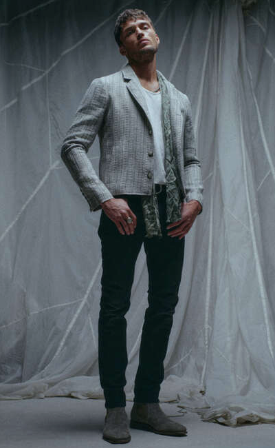 A man wearing a John Vavatos grey blazer with black pants