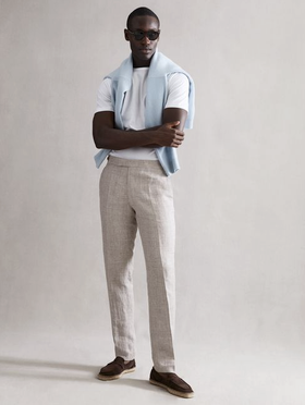 A man wearing a modern country club outfit by Reiss with a baby blue sweater draped across his shoulders