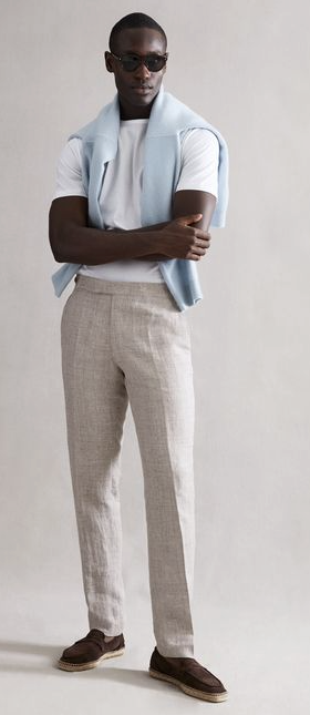 A man wearing a modern country club outfit by Reiss with a baby blue sweater draped across his shoulders