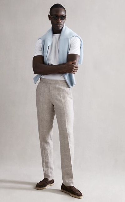 A man wearing a modern country club outfit by Reiss with a baby blue sweater draped across his shoulders