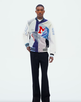 A man wearing an Amiri coaches jacket with black pants