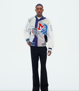 A man wearing an Amiri coaches jacket with black pants