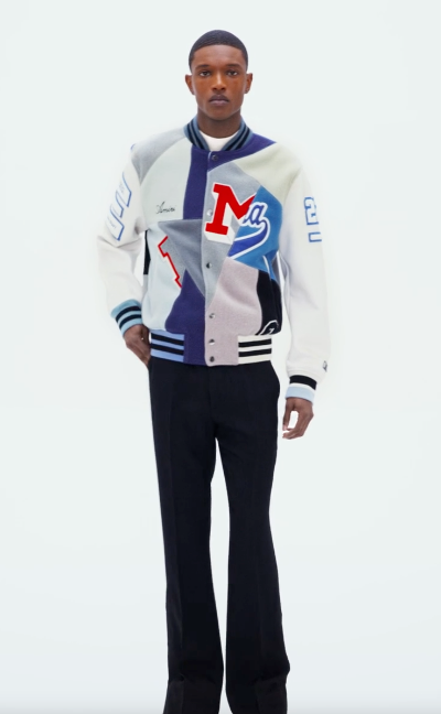 A man wearing an Amiri coaches jacket with black pants
