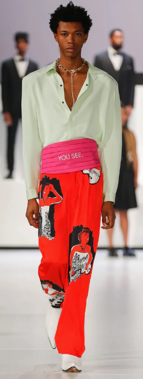 A man walking a runway wearing a avante-garde and colorful outfit from Pyer Moss