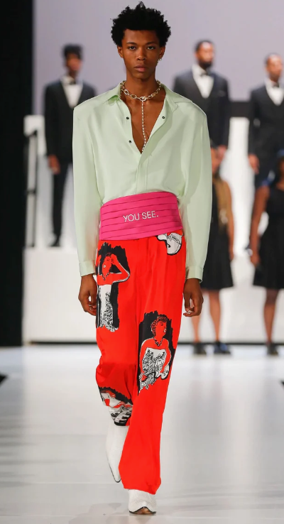 A man walking a runway wearing a avante-garde and colorful outfit from Pyer Moss