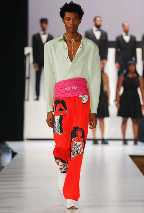 A man walking a runway wearing a avante-garde and colorful outfit from Pyer Moss