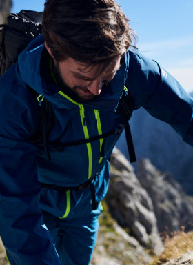 A man hiking in a blue and green Jack Wolfskin jacket and pants
