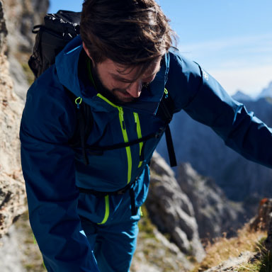 A man hiking in a blue and green Jack Wolfskin jacket and pants