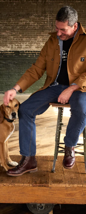 A man sitting with a dog wearing a LC King outfit featuring modern workwear