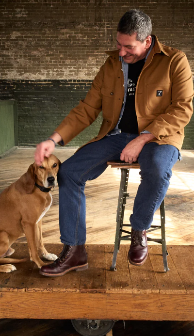 A man sitting with a dog wearing a LC King outfit featuring modern workwear