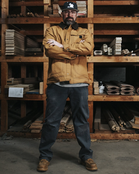 A man wearing a Wolverine brown jacket with his arms crossed