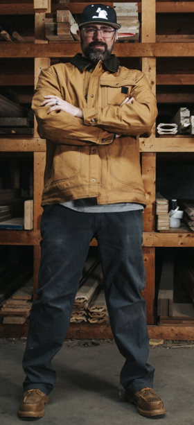 A man wearing a Wolverine brown jacket with his arms crossed