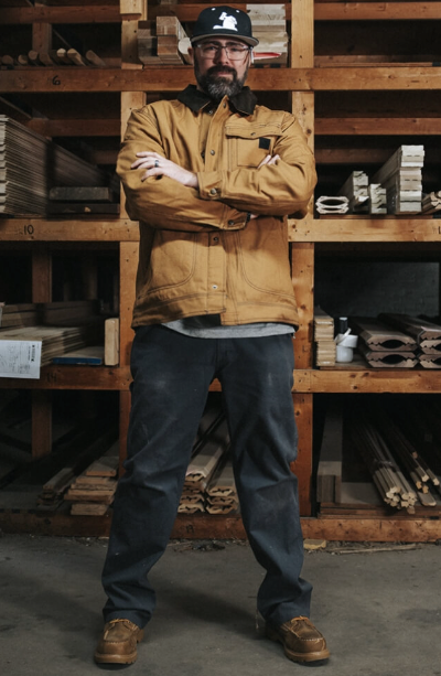 A man wearing a Wolverine brown jacket with his arms crossed
