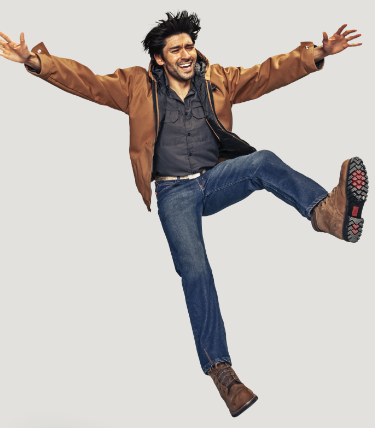 A man jumping in a brown Red Kap jacket and work boots