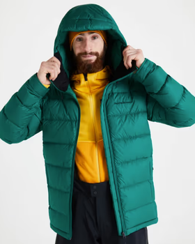 A man wearing a green puffy winter jacket along with a bright yellow fleece underneath