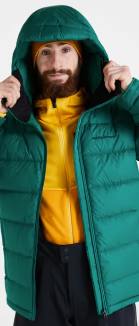 A man wearing a green puffy winter jacket along with a bright yellow fleece underneath