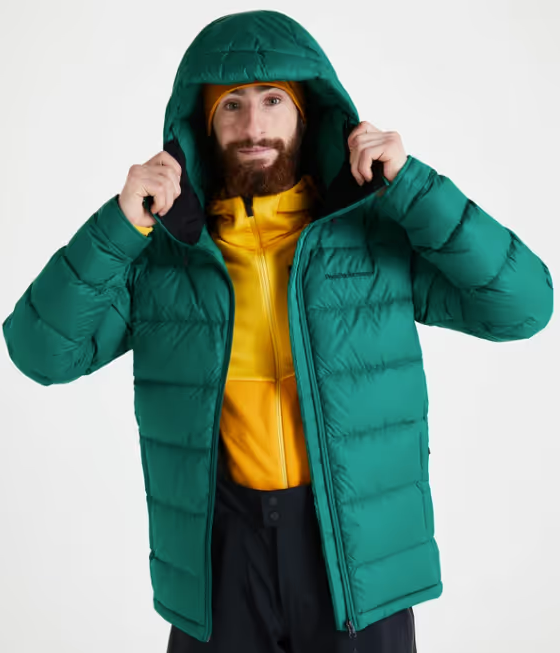 A man wearing a green puffy winter jacket along with a bright yellow fleece underneath