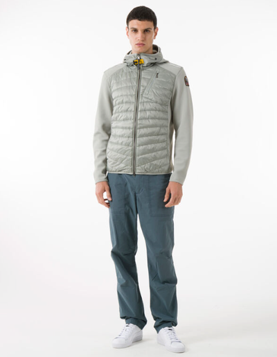 A man wearing a light grey Parajumpers puffy jacket along with blue pants and white shoes