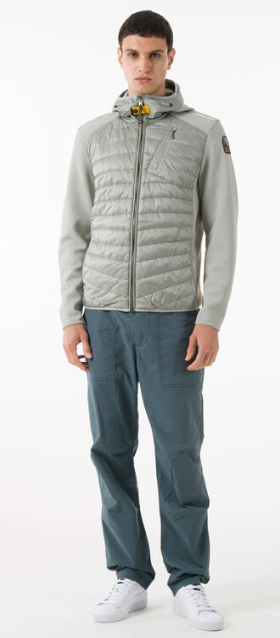 A man wearing a light grey Parajumpers puffy jacket along with blue pants and white shoes