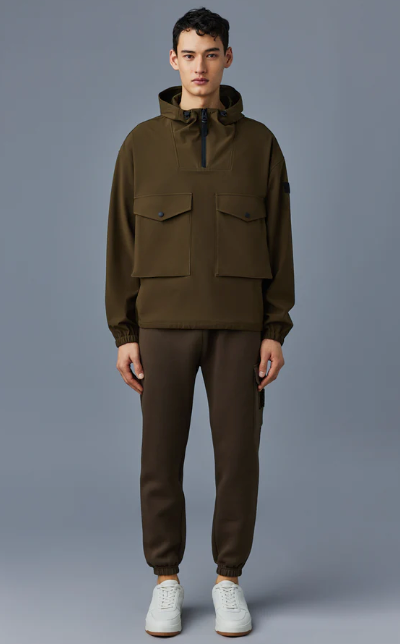 A man wearing a Mackage winter coat in olve green with sweatpants and white shoes