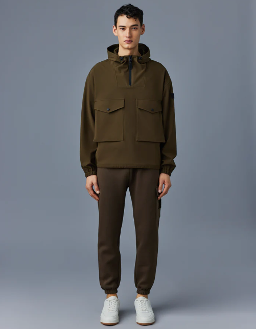 A man wearing a Mackage winter coat in olve green with sweatpants and white shoes
