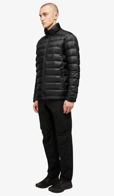 A man wearing a black Quartz Co. puffy jacket along with black pants and shoes