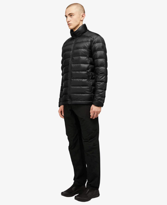 A man wearing a black Quartz Co. puffy jacket along with black pants and shoes