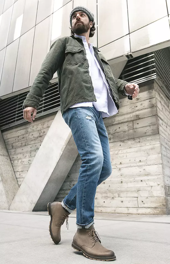A close up of a man wearing brown Frye boots