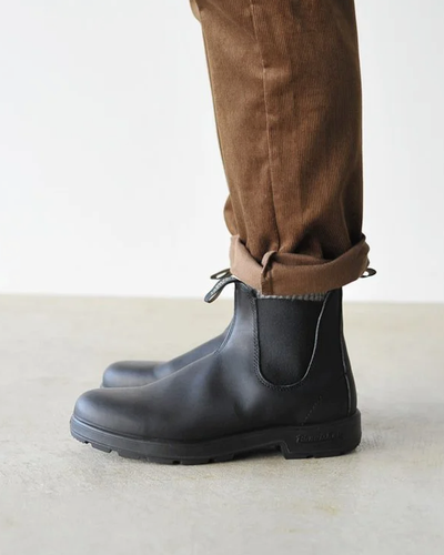 A close up of a pair of black classic Blundstones on someones feet
