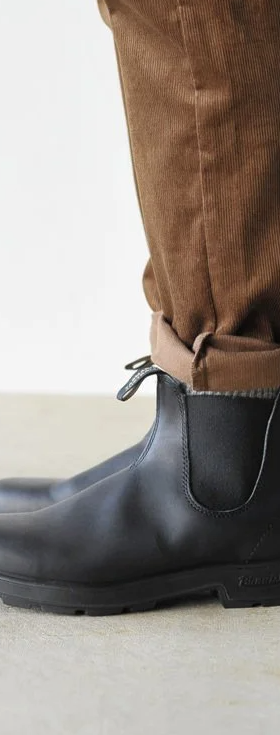 A close up of a pair of black classic Blundstones on someones feet