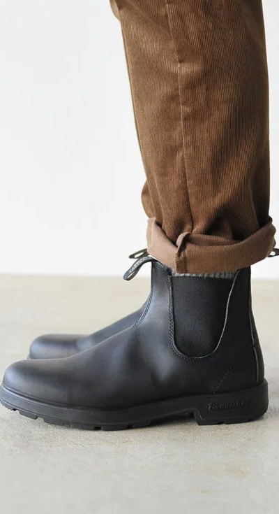 A close up of a pair of black classic Blundstones on someones feet