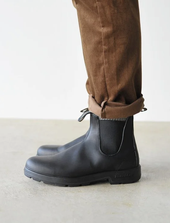 A close up of a pair of black classic Blundstones on someones feet