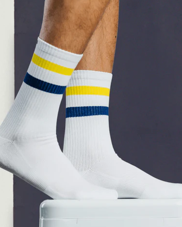 A close up of a Pair of Thieves white socks with a yellow and blue stripe