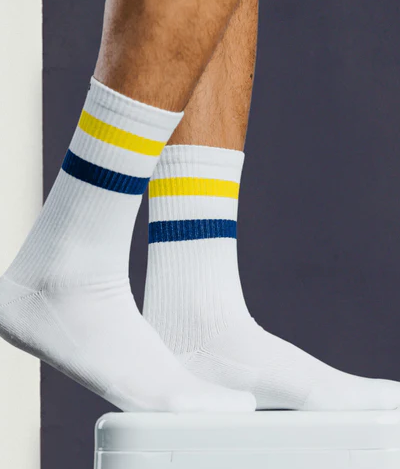 A close up of a Pair of Thieves white socks with a yellow and blue stripe