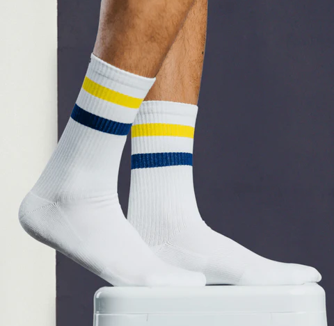 A close up of a Pair of Thieves white socks with a yellow and blue stripe