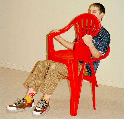 A man sitting wearing socks with a red lawn chair design on them