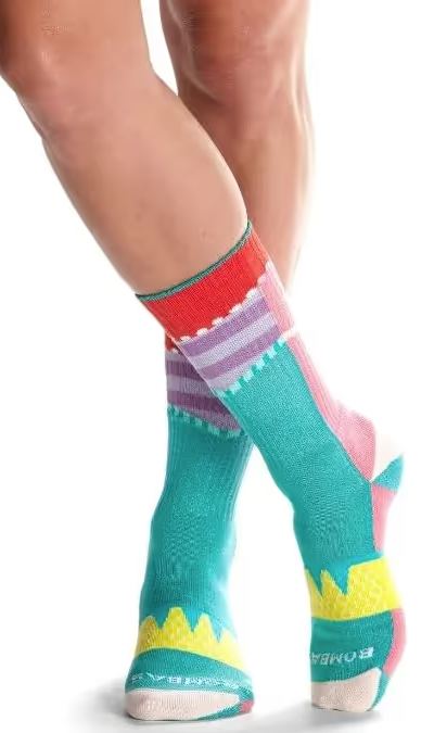 A close up of a colorful pair of bombas socks on feet