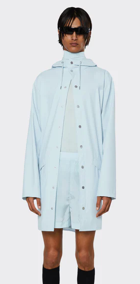 A man wearing a baby blue Rains raincoat with matching shorts and black sunglasses