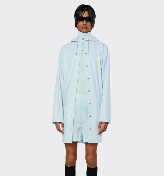 A man wearing a baby blue Rains raincoat with matching shorts and black sunglasses