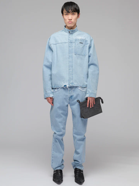 A man wearing a 032c light-wash denim jacket and pants with a blue purse