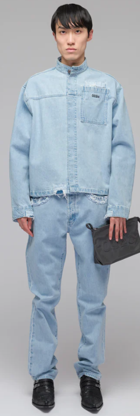 A man wearing a 032c light-wash denim jacket and pants with a blue purse
