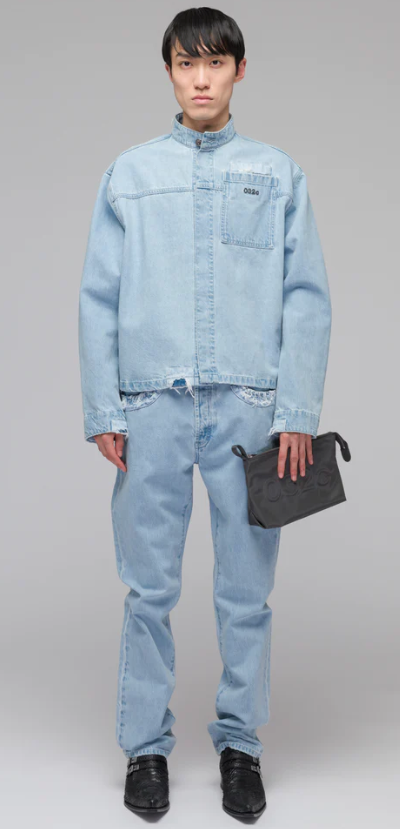 A man wearing a 032c light-wash denim jacket and pants with a blue purse