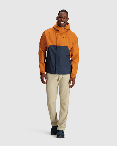 A man wearing an orange and navy blue Outdoor Research Jacket and beige pants