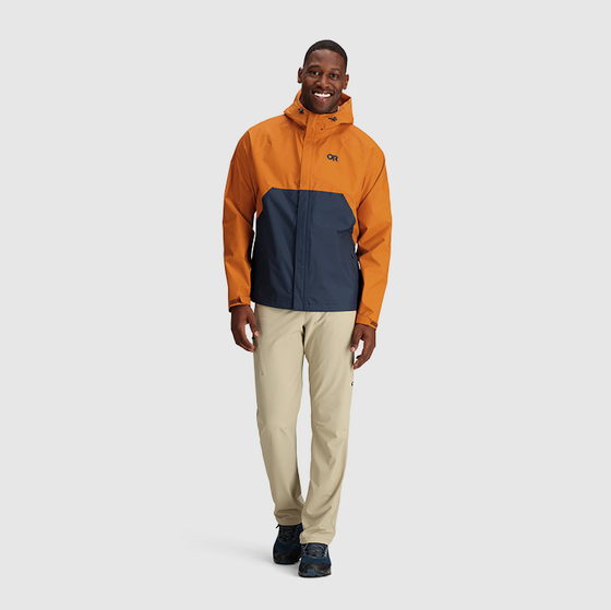 A man wearing an orange and navy blue Outdoor Research Jacket and beige pants