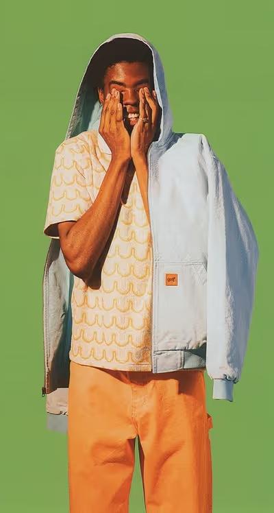 A man wearing a Golf Wang baby blue jacket and an orange button up with matching pants